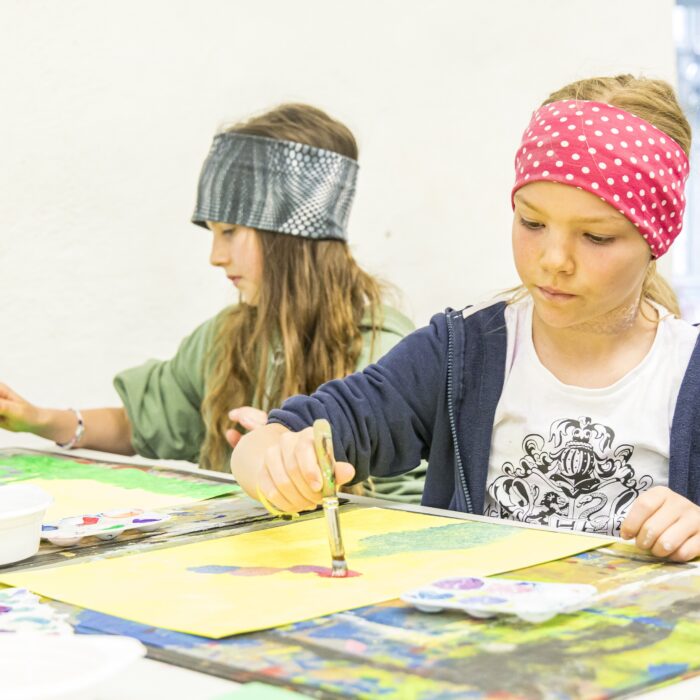 Kinder malen bei Kinderkunstworkshop mit einem Pinsel